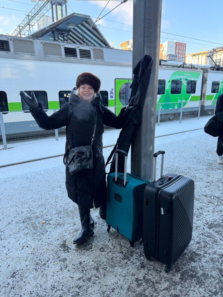 A woman with suitcases at a railway station in winter.