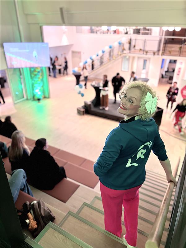 Nainen seisoo auditorion portailla, on selin kameraan mutta kääntää katseensa kameraan päin