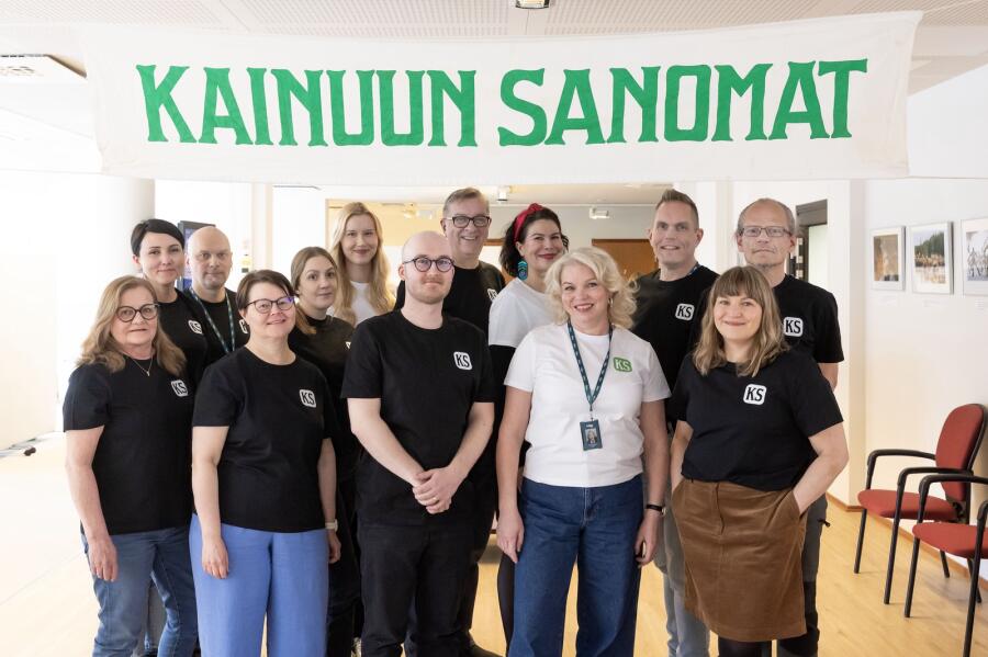 Kainuun Sanomien toimituksen yhteiiskuva, jossa useita henkilöitä ryhmäkuvassa.